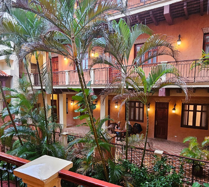 Patio interior colonial del Boutique Hotel Palacio iluminado de noche con plantas tropicales y balcones de madera
