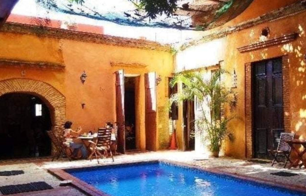 Fachada iluminada del Hotel Doña Elvira en la Zona Colonial de Santo Domingo, mostrando la entrada de estilo colonial con arco de ladrillo y el letrero principal por la noche