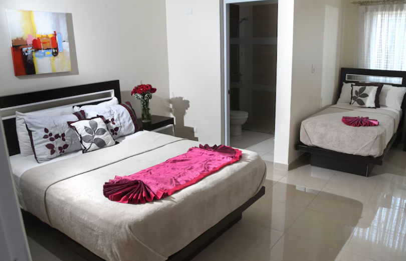 Fachada del Hostal San Francisco de Asís en Santo Domingo con su letrero rojo distintivo, entrada principal y balcones