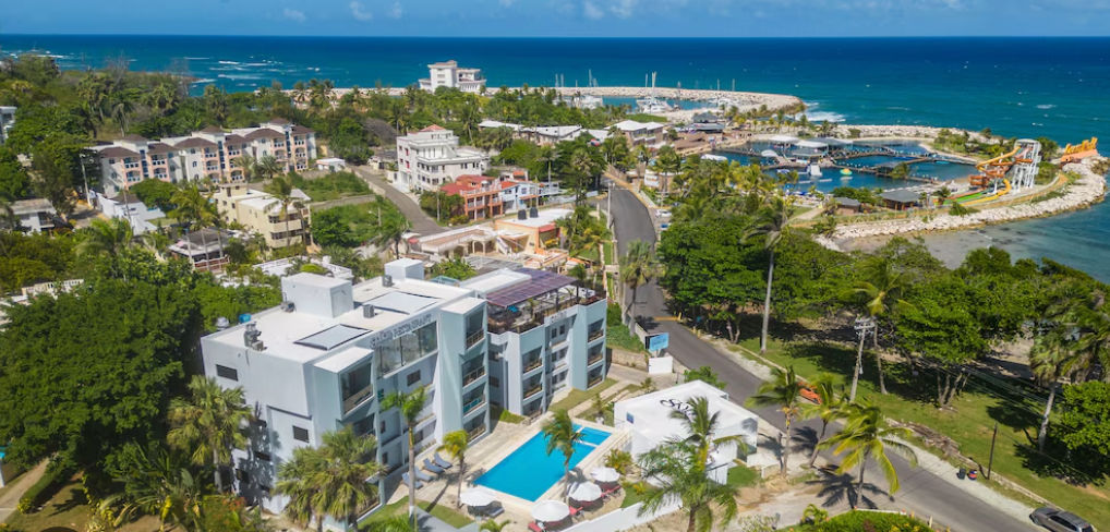 Main facade of Skylight Restaurant in Puerto Plata, featuring a modern pale blue building with large glass windows, balconies, and palm trees under a clear sky.
