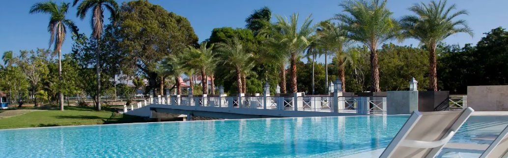 Vista aérea del resort VH Atmosphere Adults Only en Playa Dorada, mostrando la piscina, el puente sobre el lago y el campo de golf junto al mar
