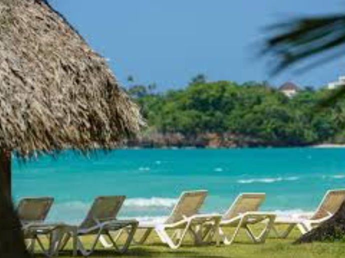 Outdoor terrace with wooden dining tables and white colonial-style architecture of Hotel Atlantis in Las Terrenas