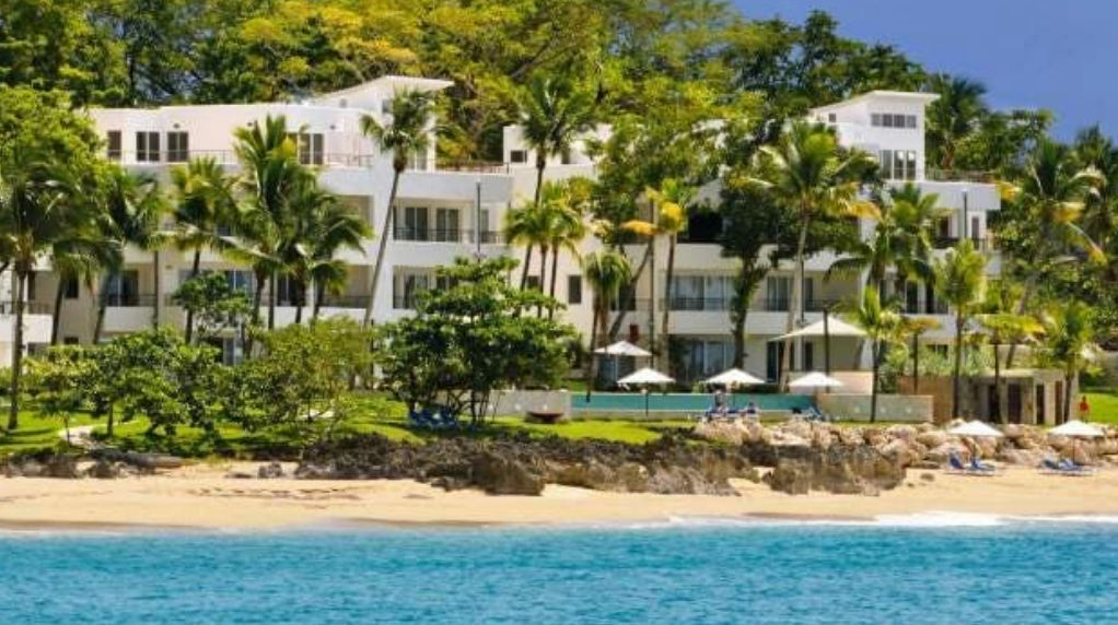 Piscina de borde infinito en Infinity Blu Sosua frente al mar rodeada de palmeras y tumbonas / Infinity pool at Infinity Blu Sosua facing the ocean surrounded by palm trees and lounge chairs