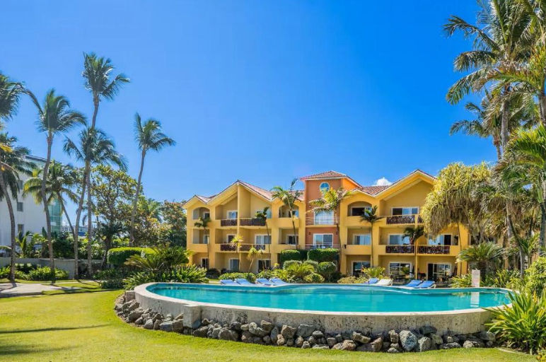Outdoor swimming pool at Agualina Kite Resort surrounded by tropical gardens and palm trees under a clear blue sky