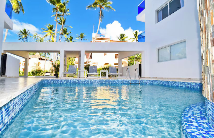 The Sanctuary at Los Corales facade in Punta Cana with blue glass balconies and palm trees
