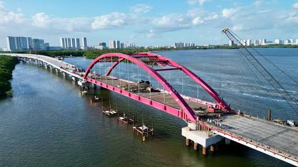 Puente Vehicular Nichupté en construcción con arco rosa sobre la laguna de Cancún