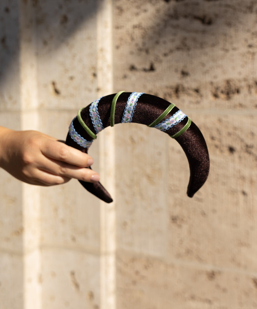 A person holding a WALD Berlin Headband Swirl Dark Brown.