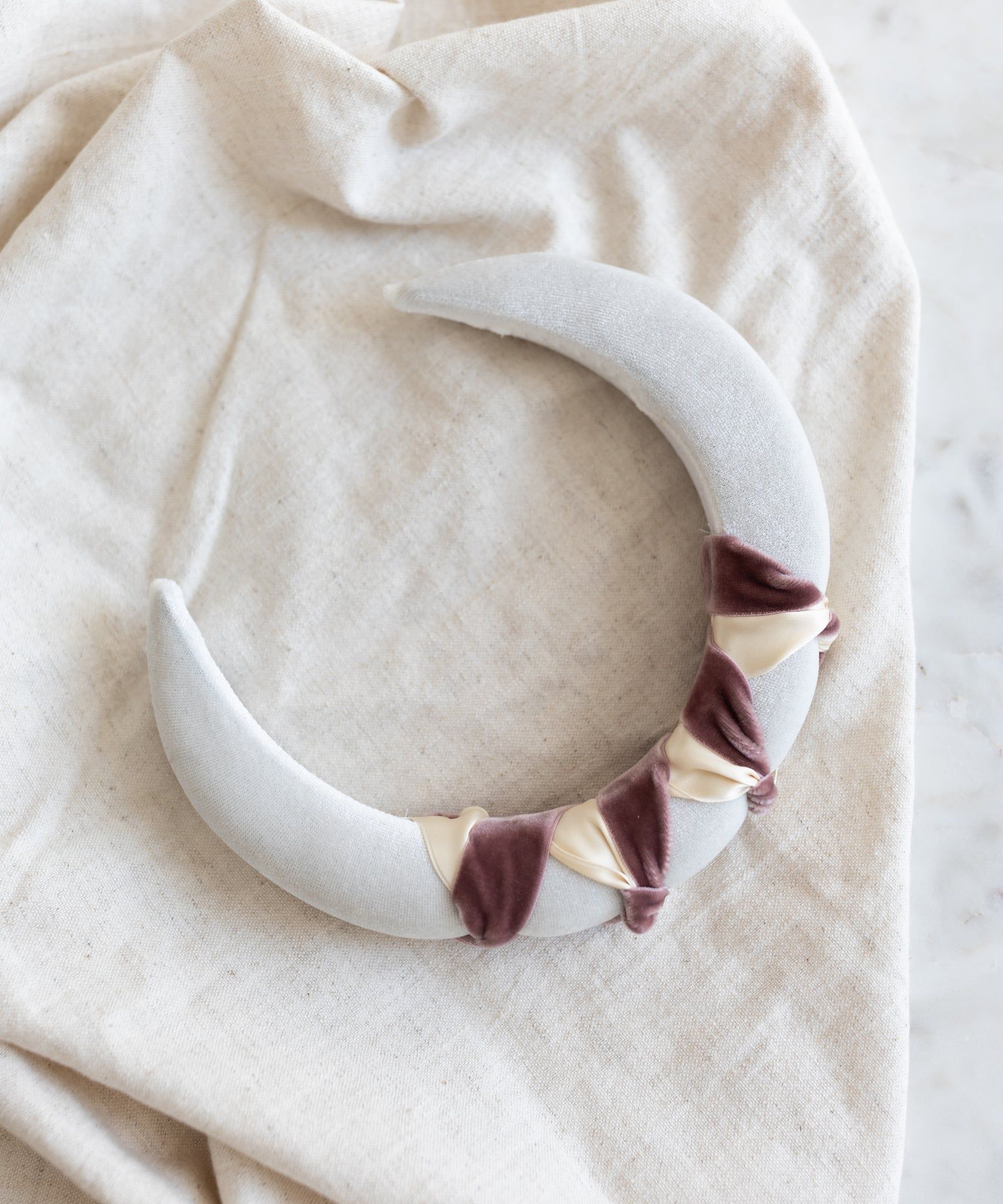A Headband Knot White necklace by WALD Berlin on a white cloth.