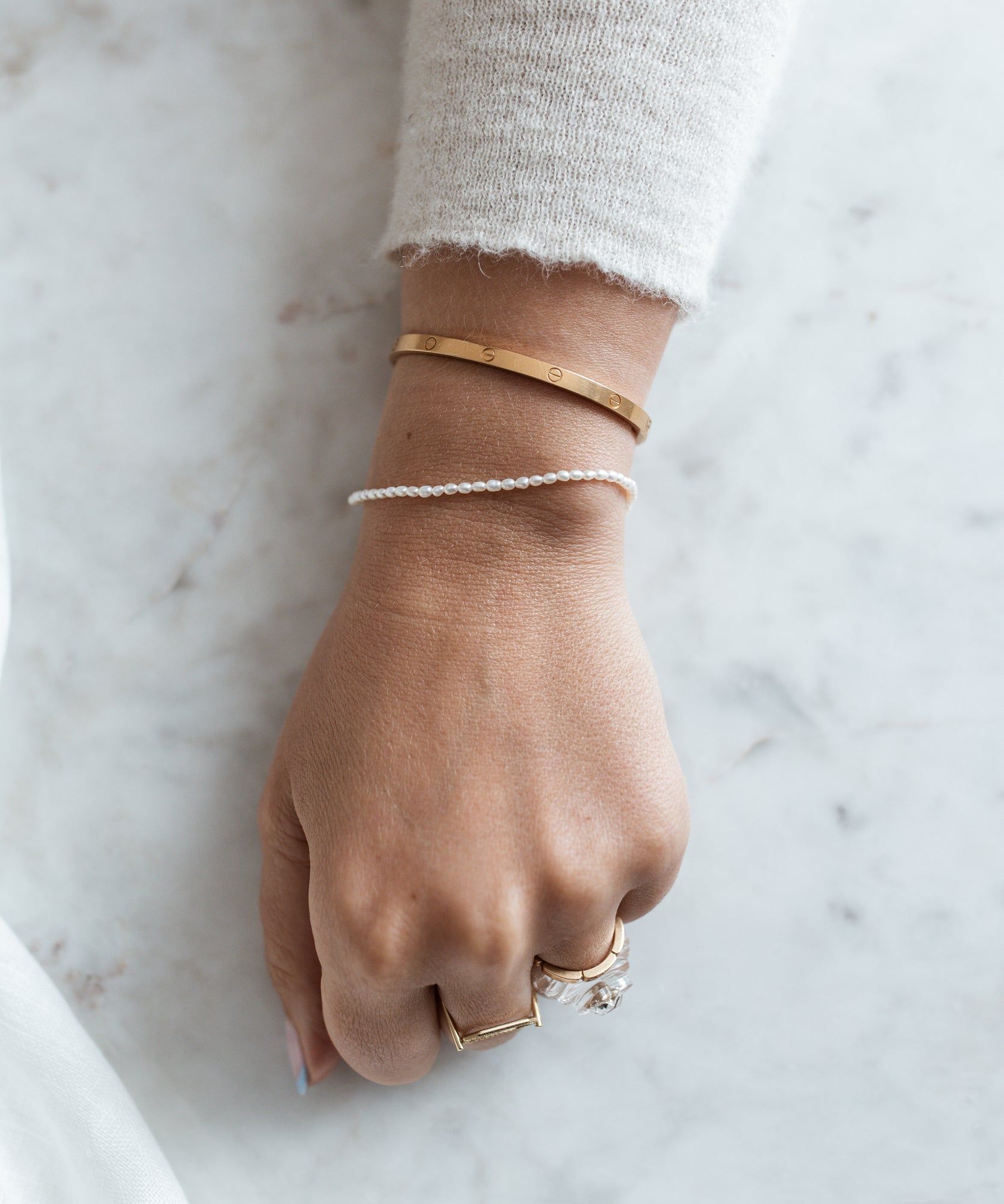 A woman's hand adorned with a WALD Berlin Fine Rice Pearl Bracelet showcases exquisite German jewelry.