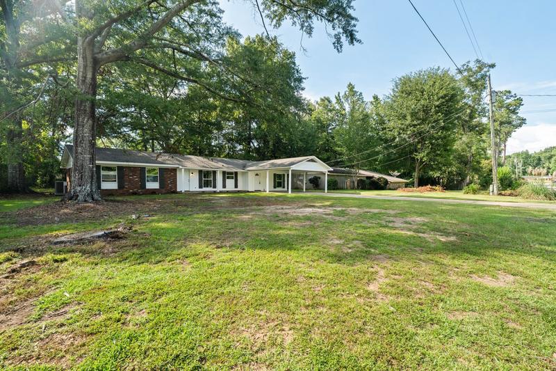 Wide front-yard view with mature trees and the single-story home