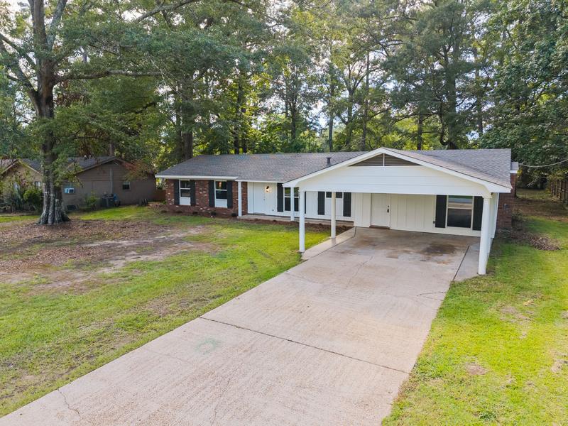 Elevated front view showing the driveway, carport, and roofline
