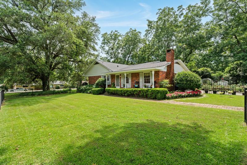 The brick ranch seen from the west yard, shaded by mature trees