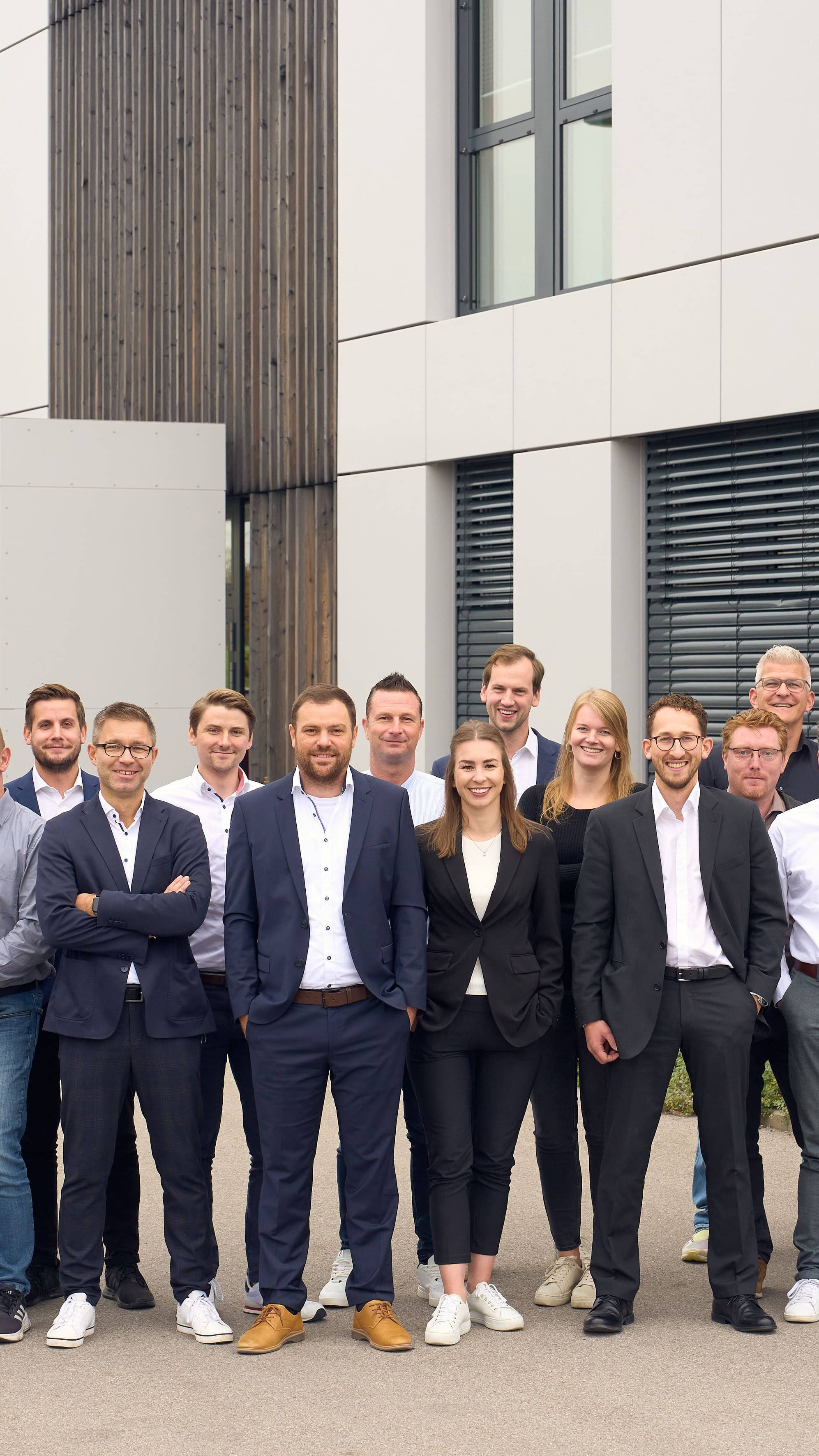 Gruppe von Geschäftsleuten posiert vor einem modernen Bürogebäude.