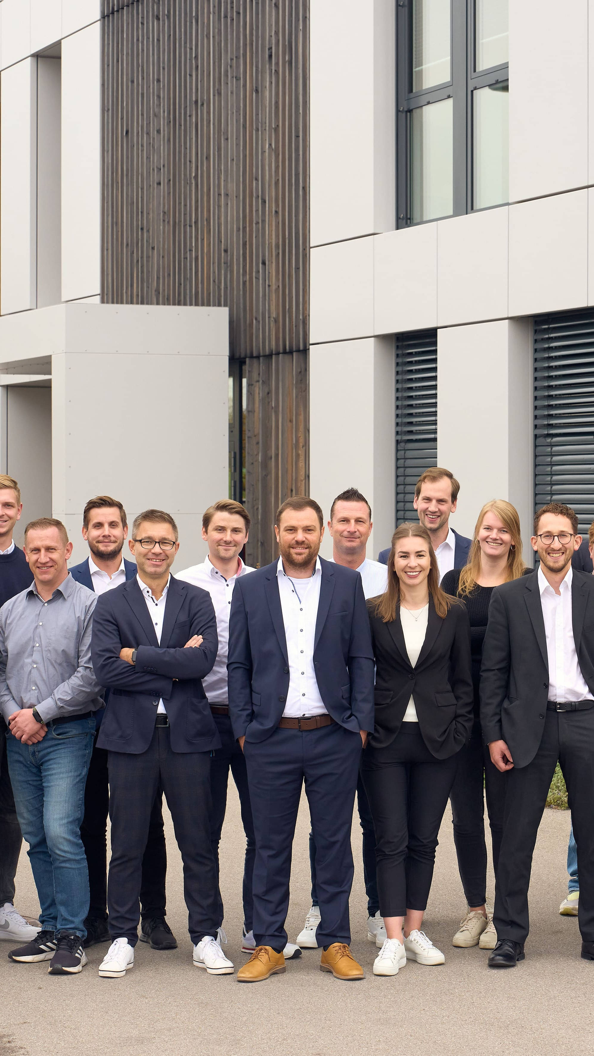Gruppe von Geschäftsleuten posiert vor einem modernen Bürogebäude.