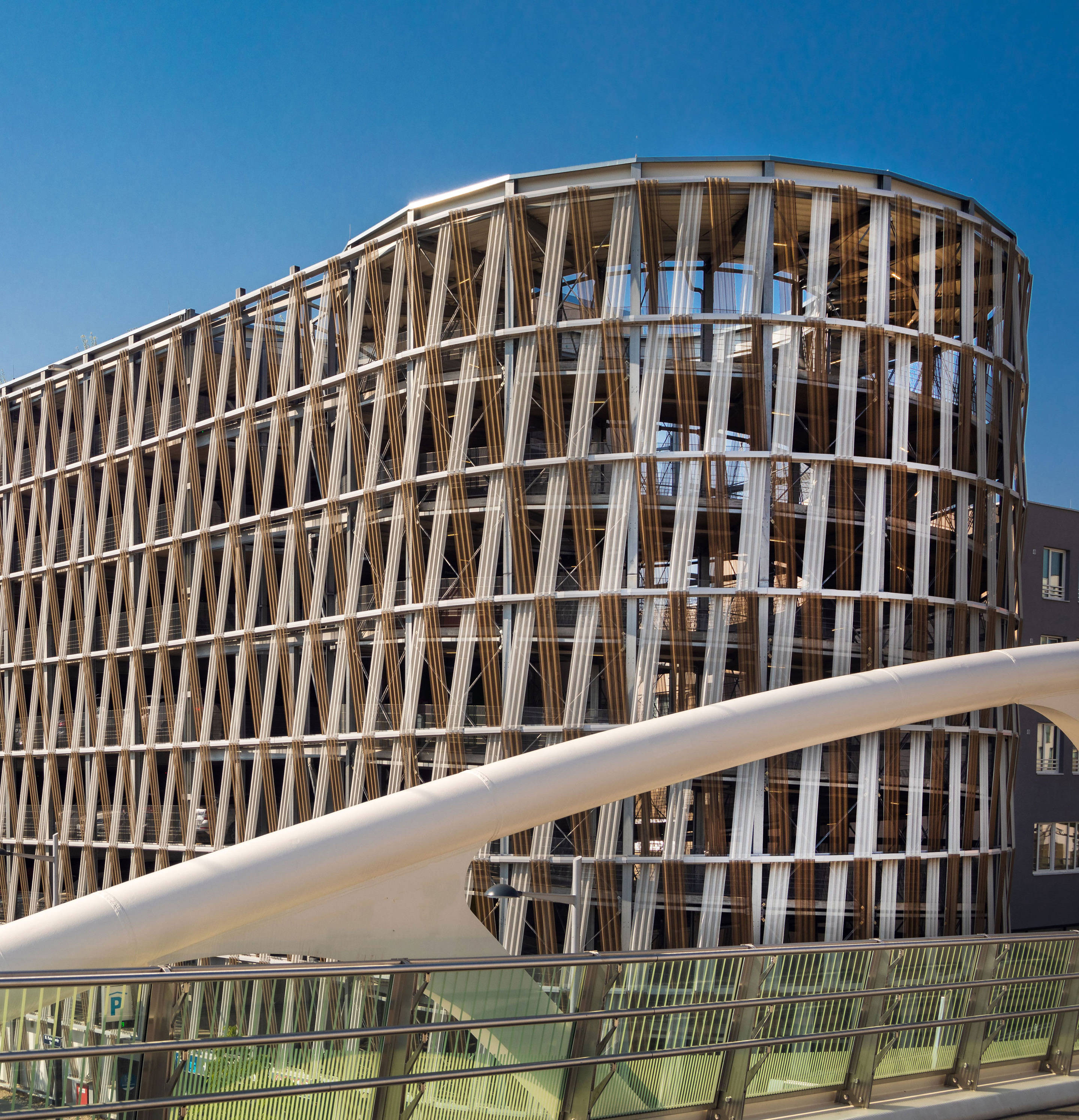 Modern parking garage with a unique V-shaped façade in an urban neighborhood under a bright blue sky.