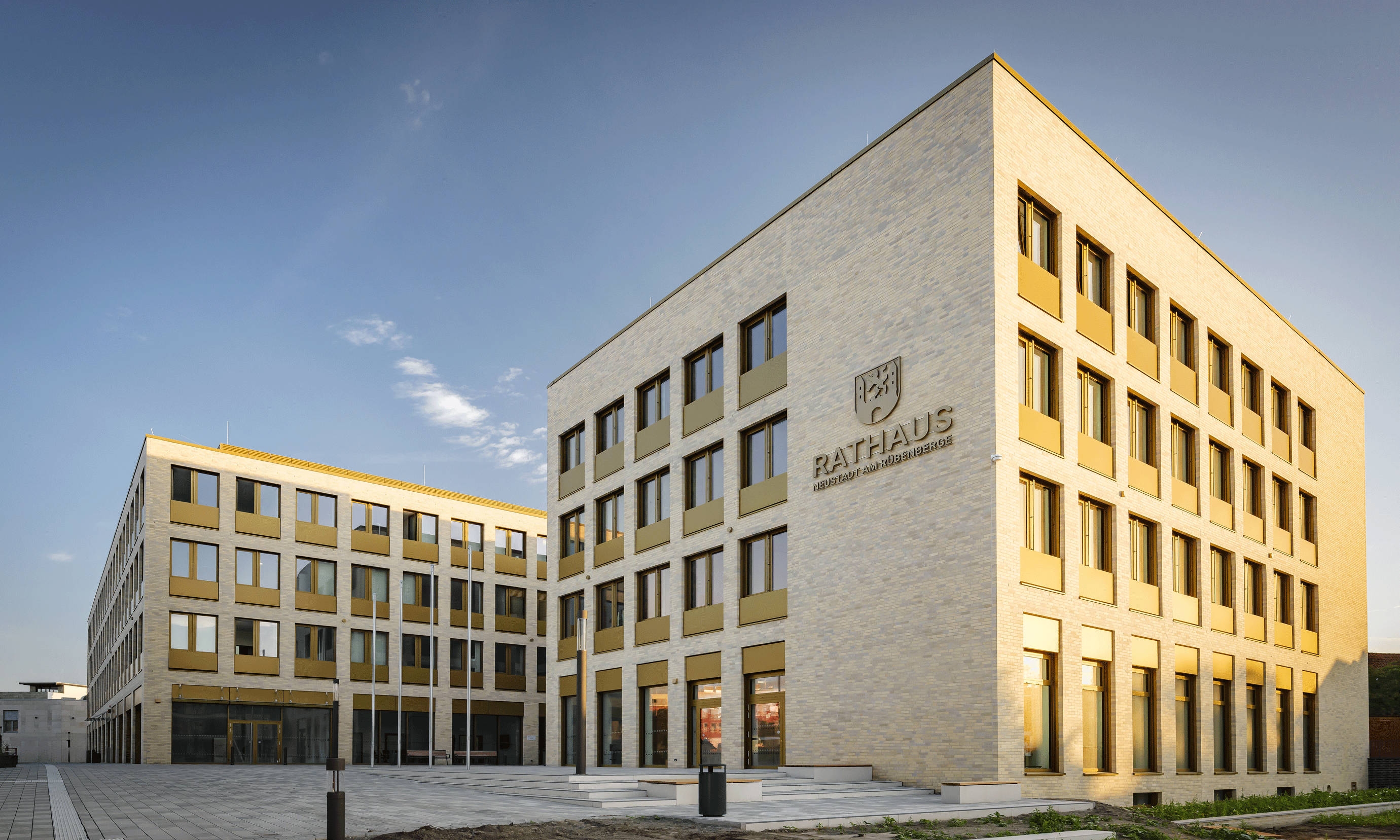 Modern town hall building made of beige brick with large windows by day.