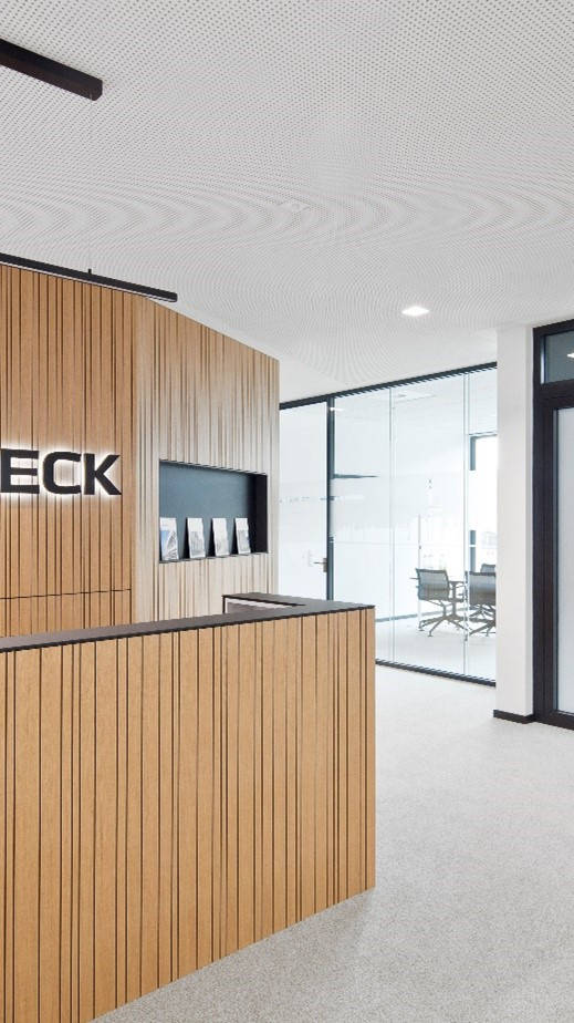 Empfangsbereich eines modernen Bürogebäudes mit Holzverkleidung und beleuchtetem Schriftzug "Goldbeck".