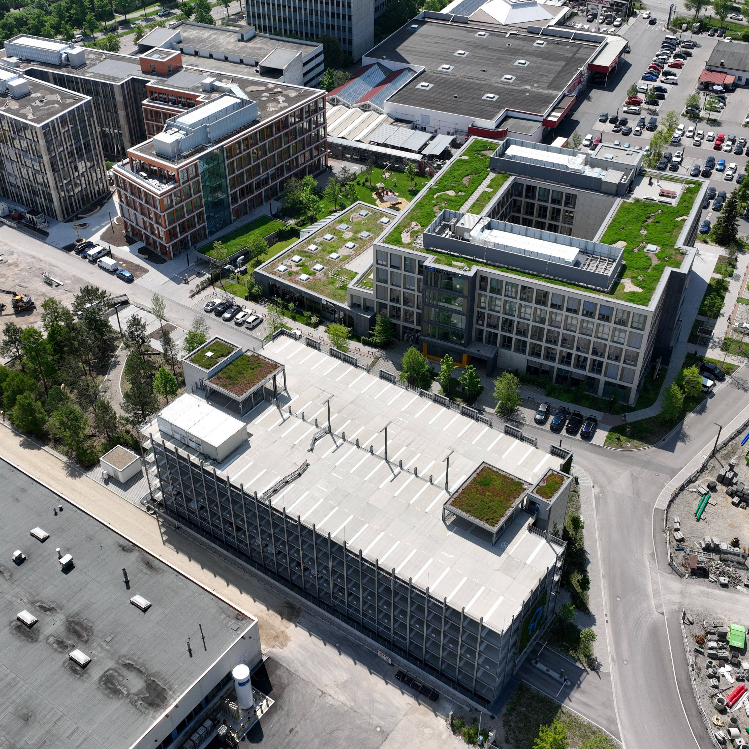 Luftaufnahme eines städtischen Gewerbegebiets mit modernen Bürogebäuden, begrünten Dächern und einem Parkplatz.