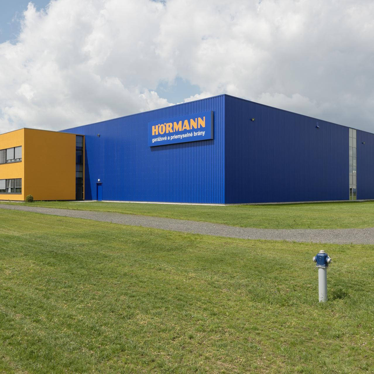 Eine Logistikhalle mit einer dunkelblauen Fassade und der gelben Aufschrift “Hörmann“