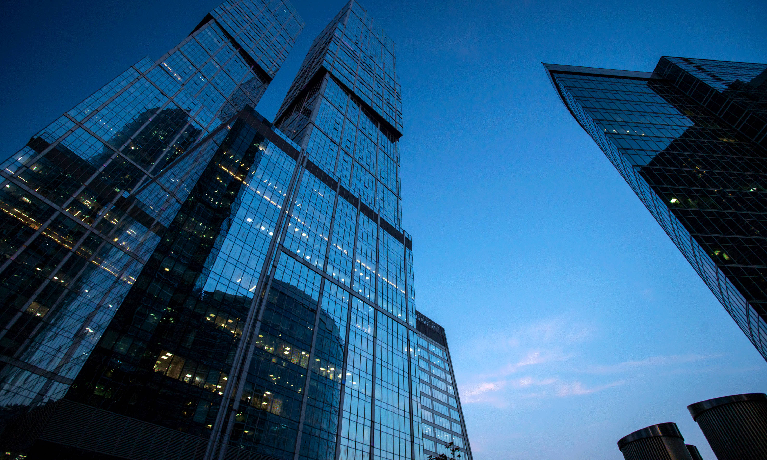 Modern glass skyscrapers against a blue sky at dusk.