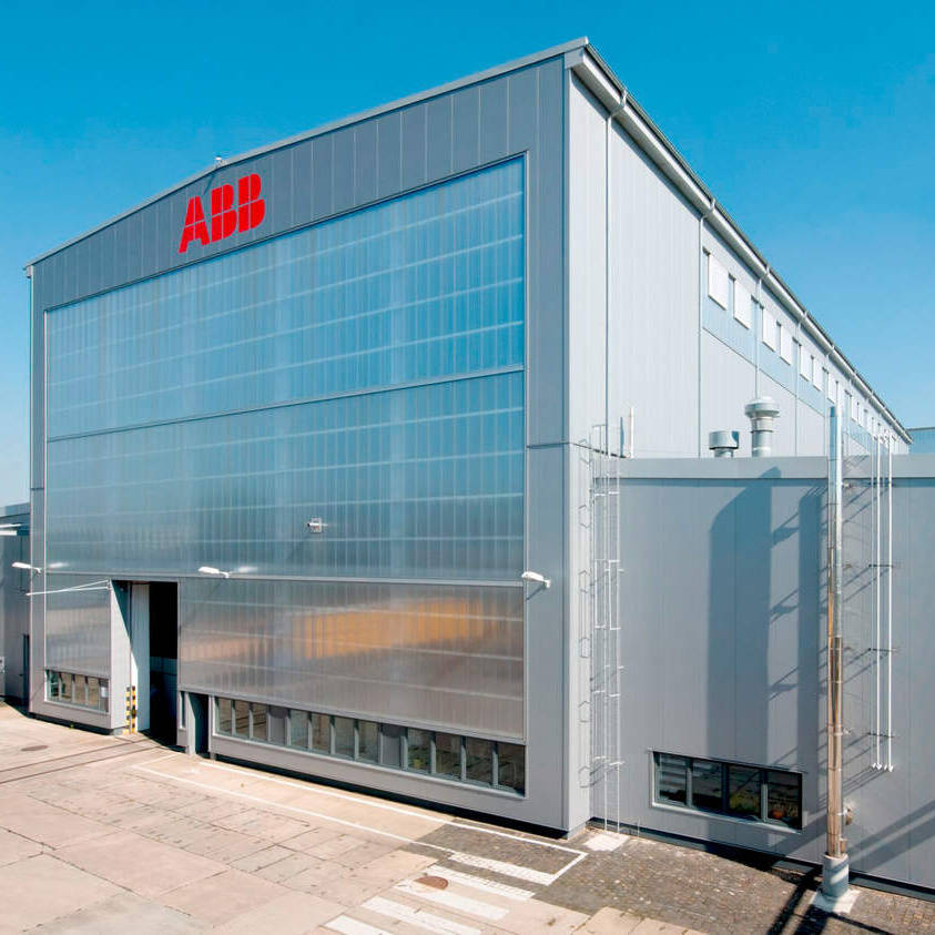 Industrial building with gray facade and company logo on the front, blue sky in the background.