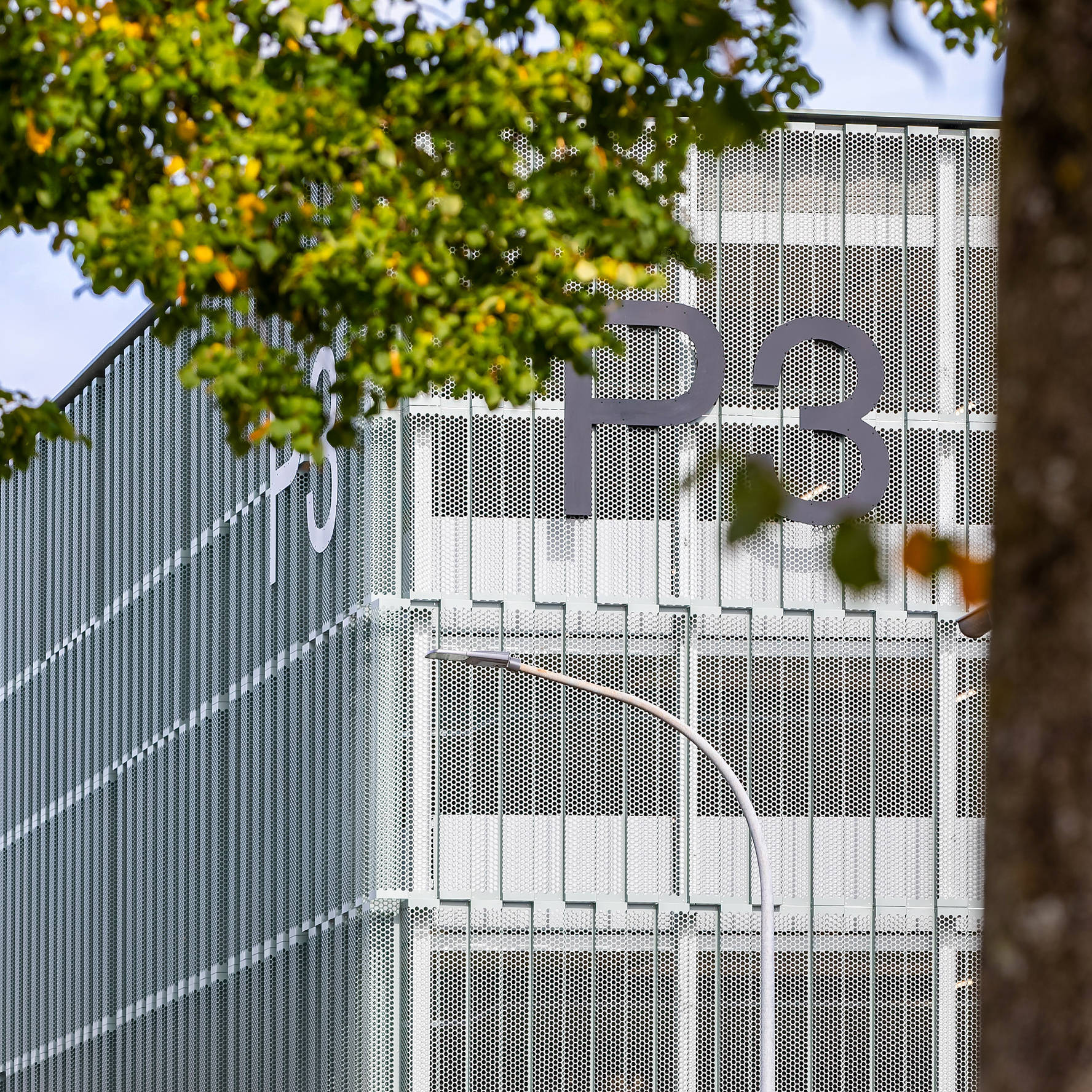 Close-up view of the Quartiershub P3 with a view of the façade through trees.