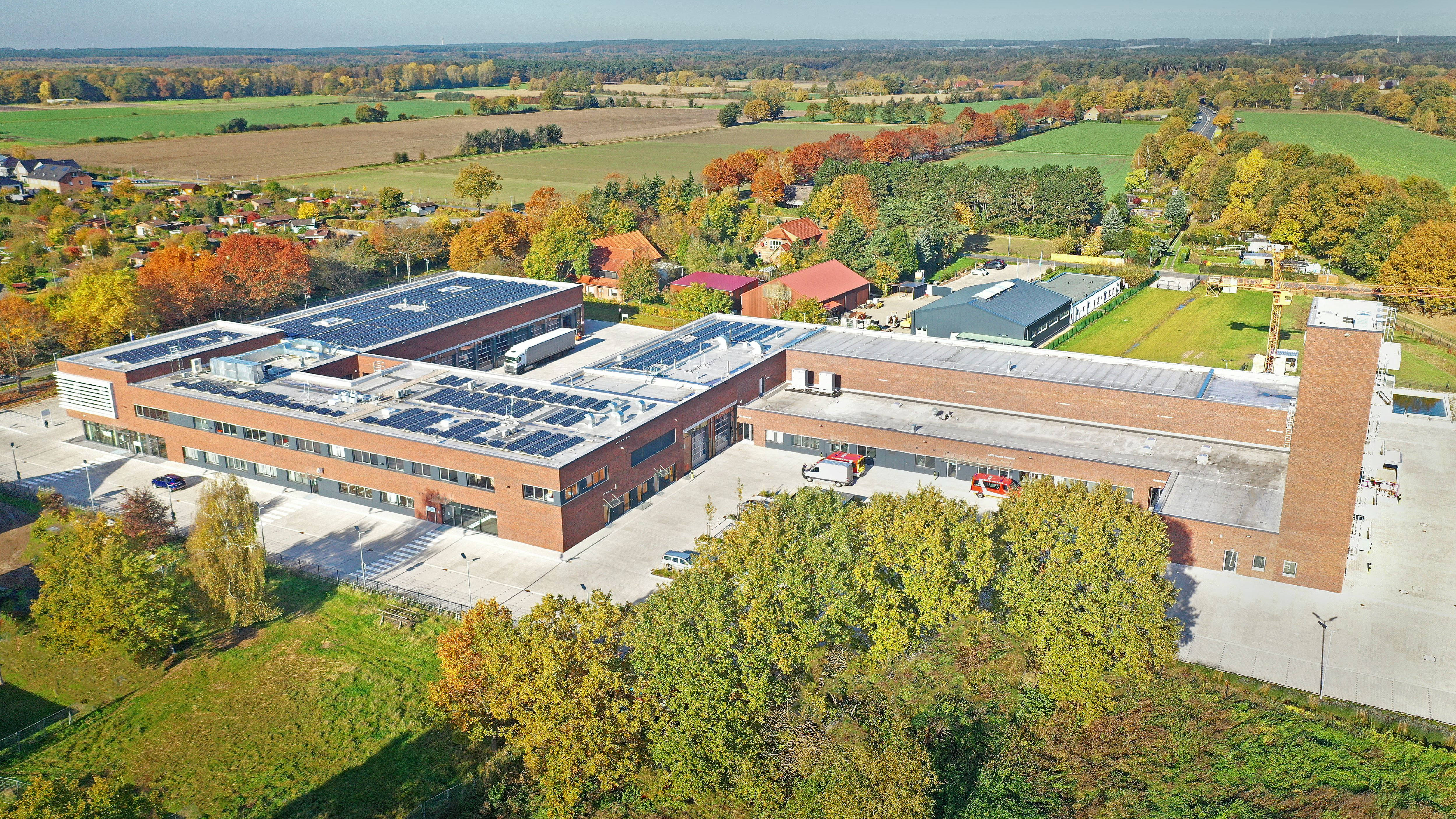 Luftaufnahme eines Feuerwehrgebäudes mit Solarpanelen auf dem Dach.
