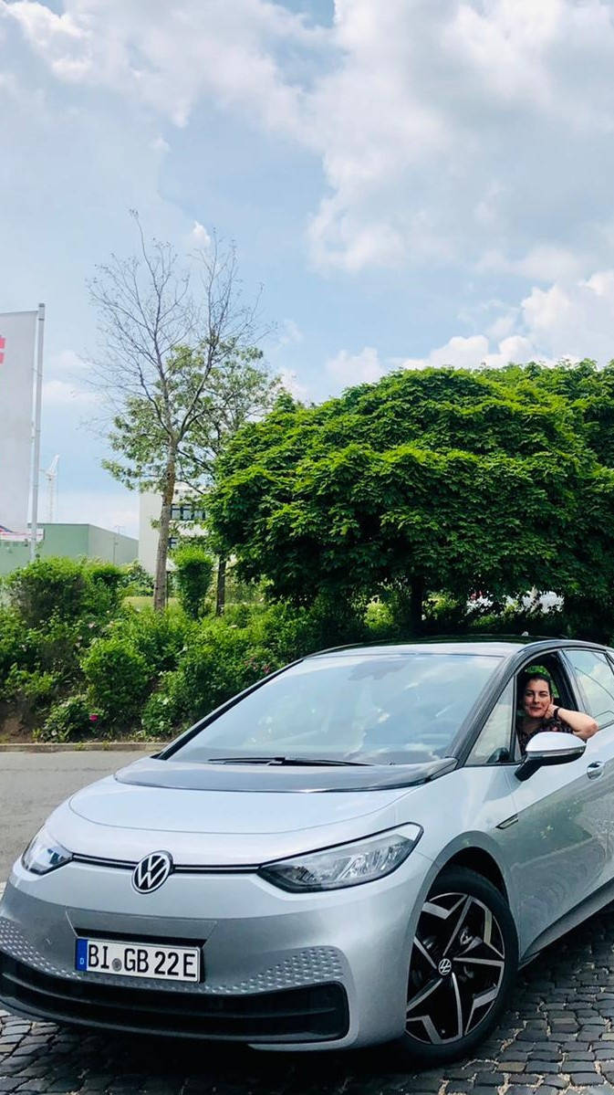 Silberner Volkswagen ID.3, geparkt auf einem Campus, vor einem grünen Baum und einer blauen GOLDBECK-Flagge.