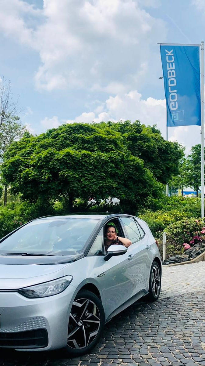 Silberner Volkswagen ID.3, geparkt auf einem Campus, vor einem grünen Baum und einer blauen GOLDBECK-Flagge.