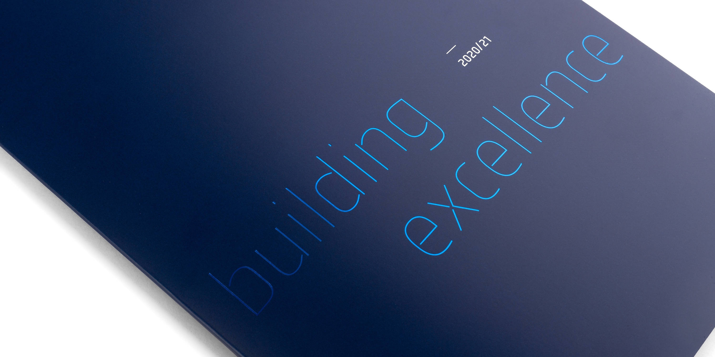 Blauer Broschüre-Titel mit der Aufschrift "building excellence 2020/21" in heller Schrift.