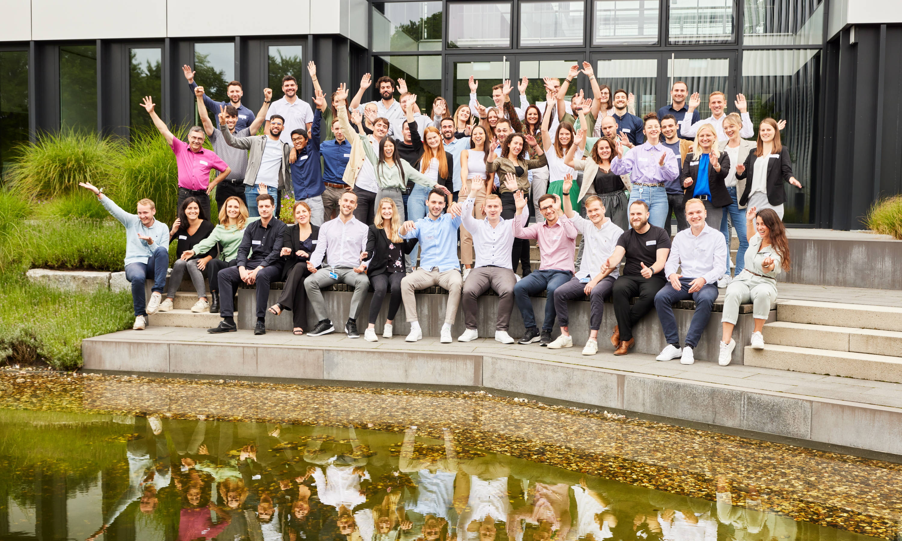 gruppenfoto von einem gruppenevent vor einem gebäude eines unternehmens vor einem teich