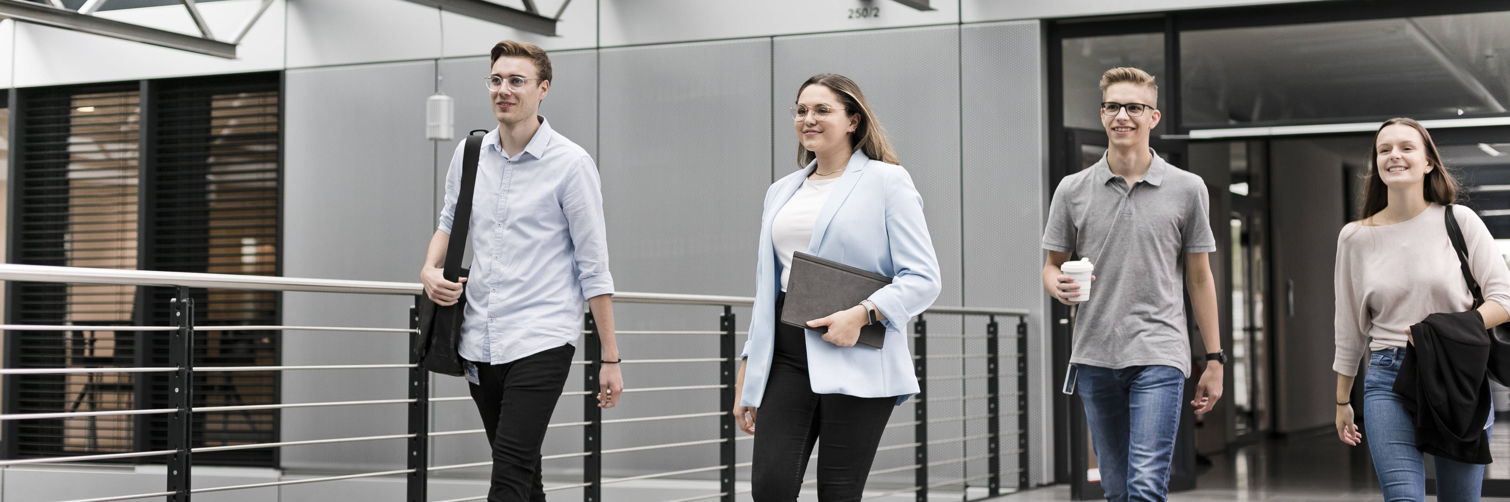 vier leute aus dem büro gehen einen flur entlang