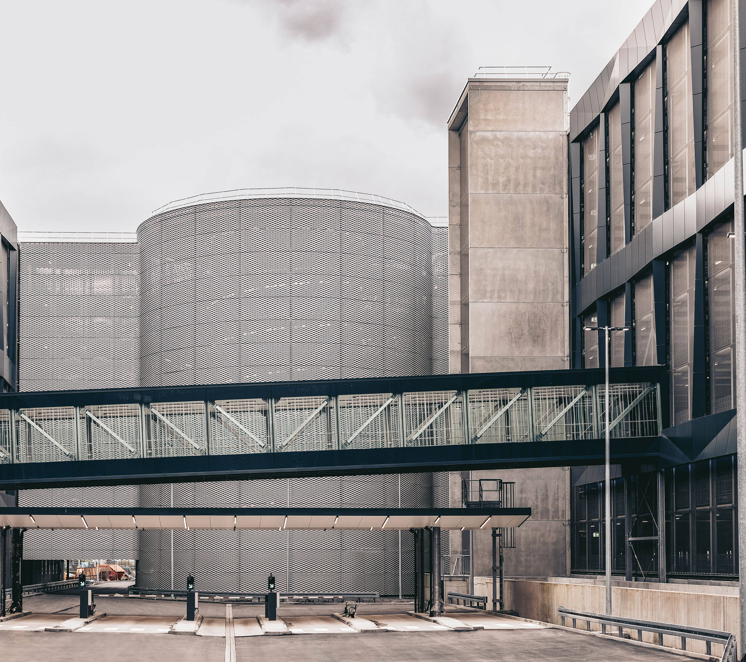 Modern industrial building with glazed facades and external staircases, under a cloudy sky.