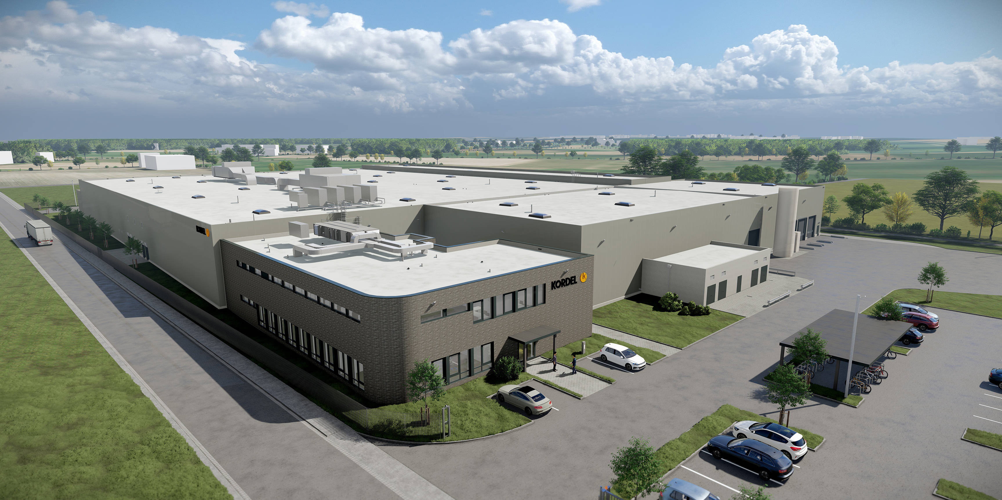 Moderne Industrieanlage mit Flachdach in ländlicher Umgebung, umgeben von Parkplätzen und Grünflächen bei sonnigem Wetter.