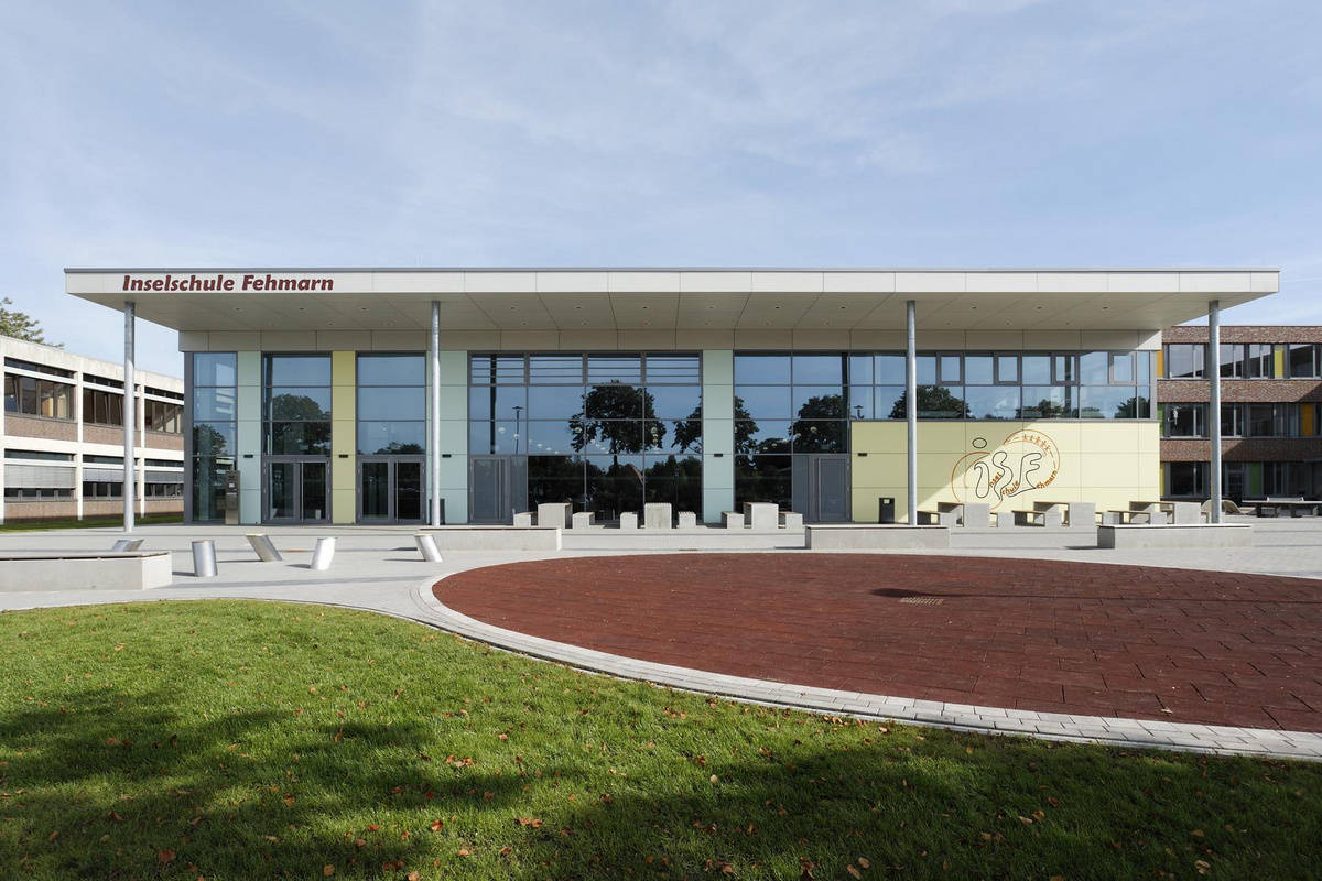 Moderne Fassade der Inselschule Fehmarn mit großflächigen Glasfenstern und einem weitläufigen Eingangsbereich.