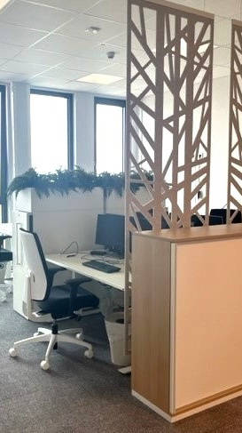 Modernes Büro mit zwei schlichten, schwarzen Bürostühlen und einem Raumteiler mit Baumdesign.