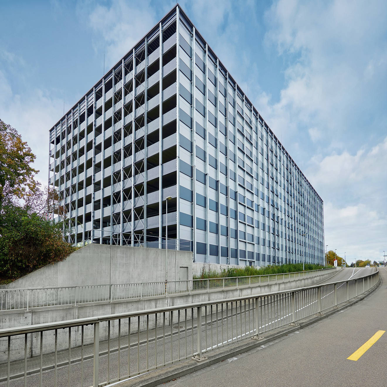 Mehrstöckiges Parkhaus aus Beton und Glas mit Rampen und Geländern.
