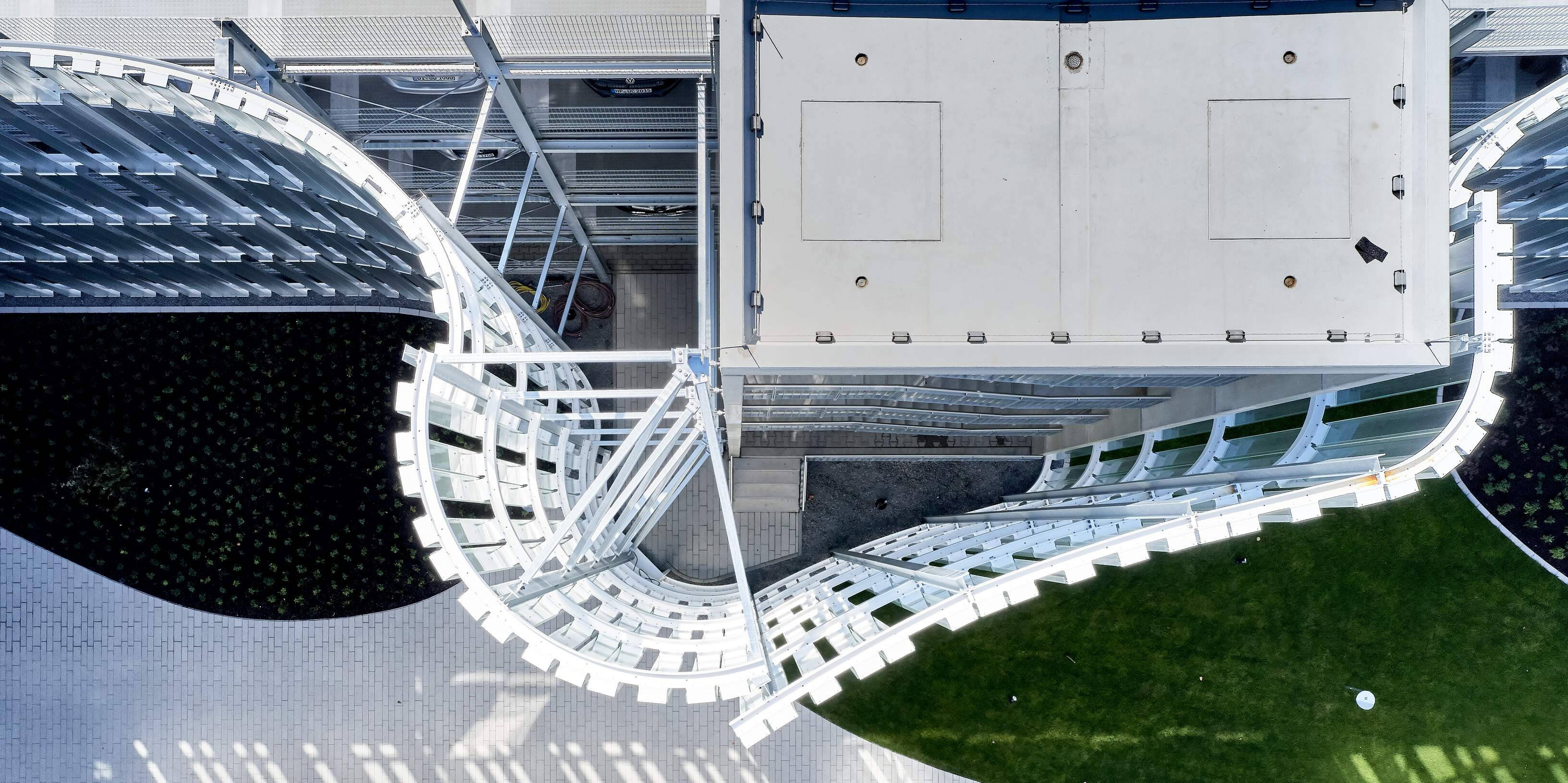 Luftaufnahme eines modernen Gebäudekomplexes mit geschwungenen, weißen Strukturen und grünen Rasenflächen.