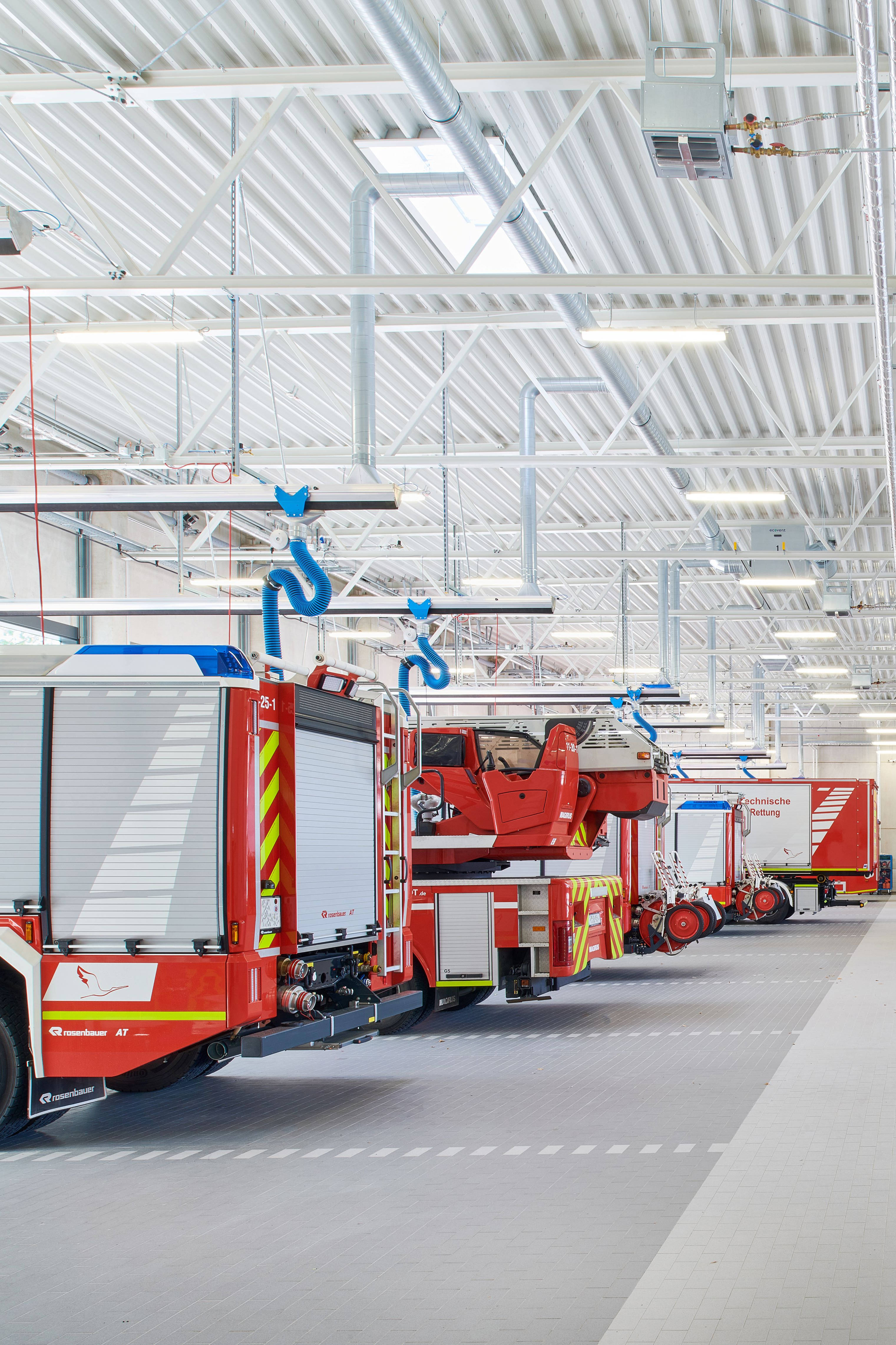 Innenansicht einer Garage, in dem mehrere rote Feuerwehrfahrzeuge abgestellt sind.