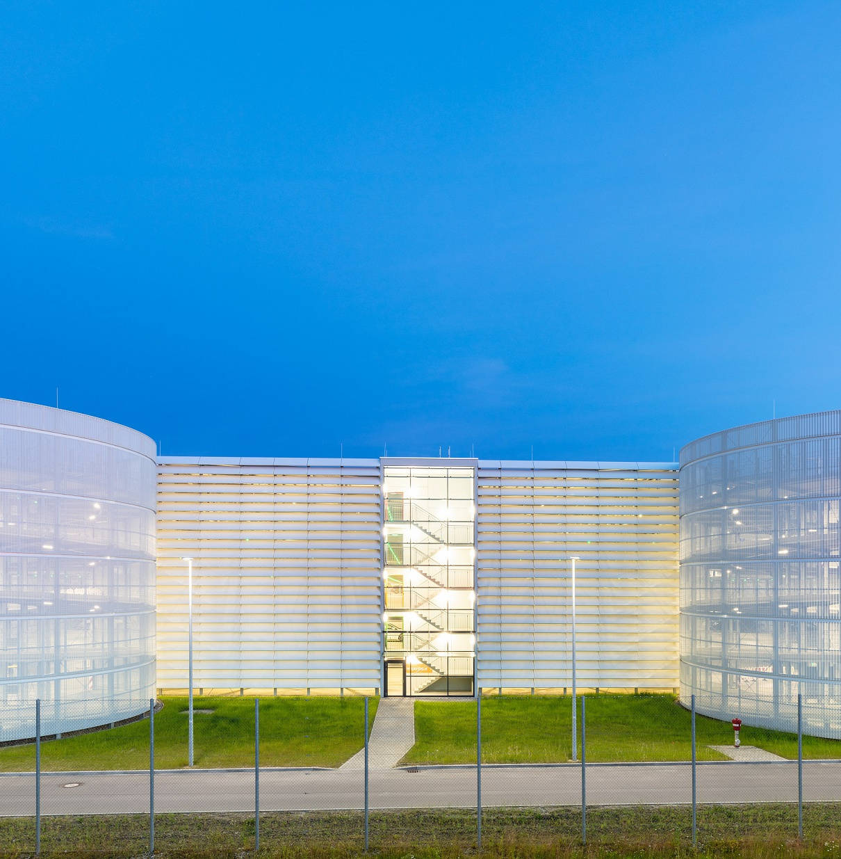 Modern office building with glazed façade and lawns at dusk.