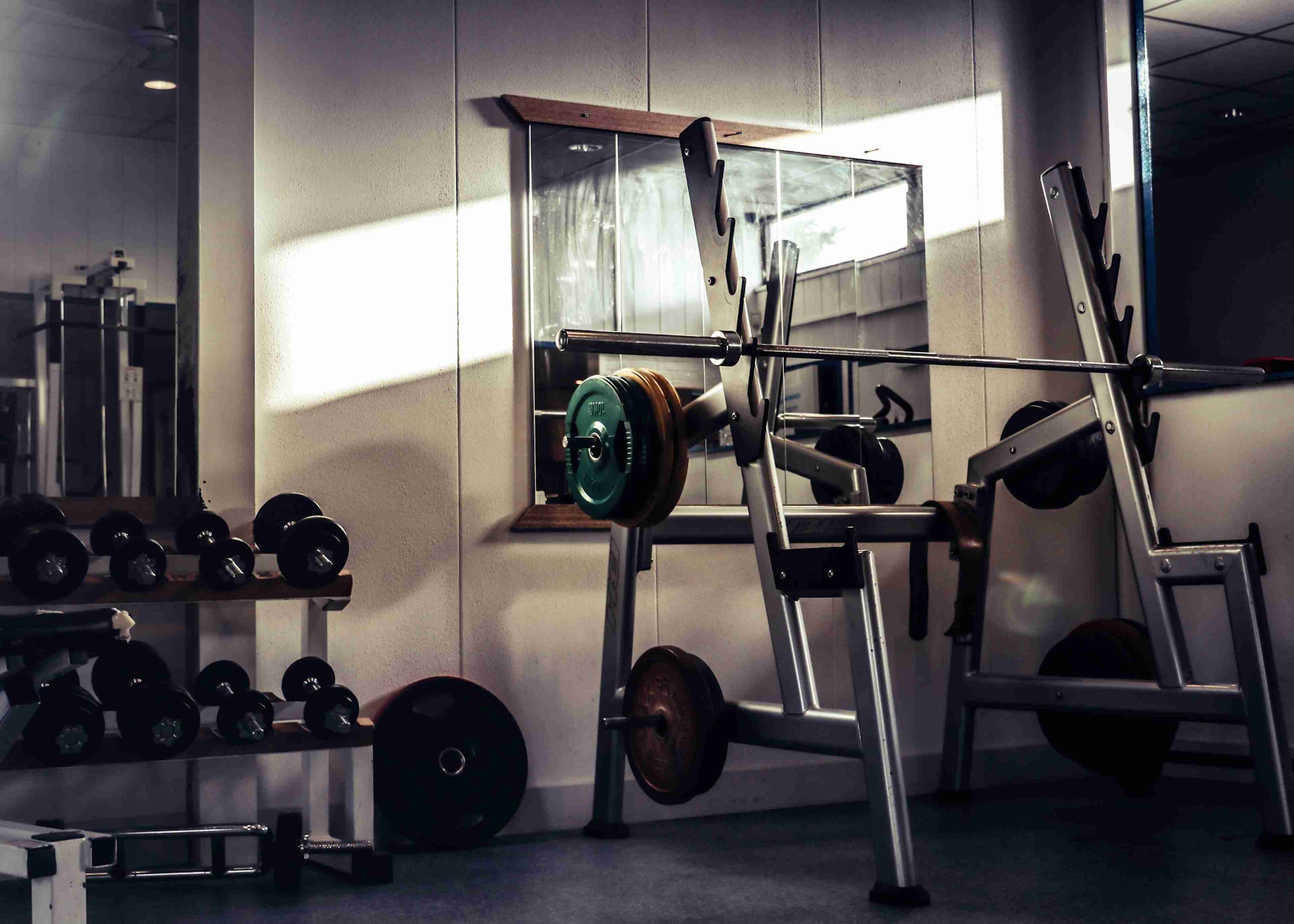 An indoor gym with sunlight streaming through a window onto weightlifting equipment