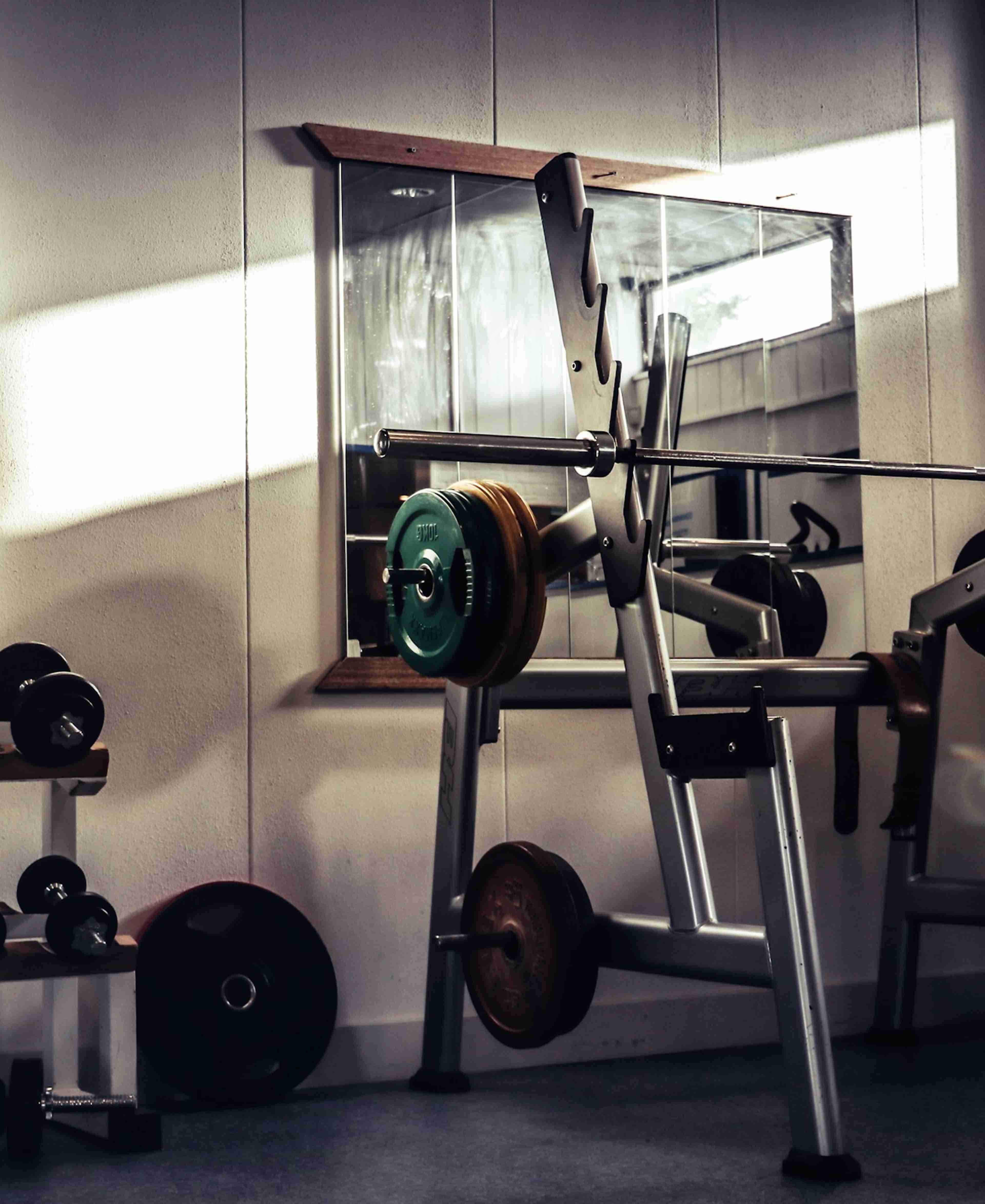 An indoor gym with sunlight streaming through a window onto weightlifting equipment
