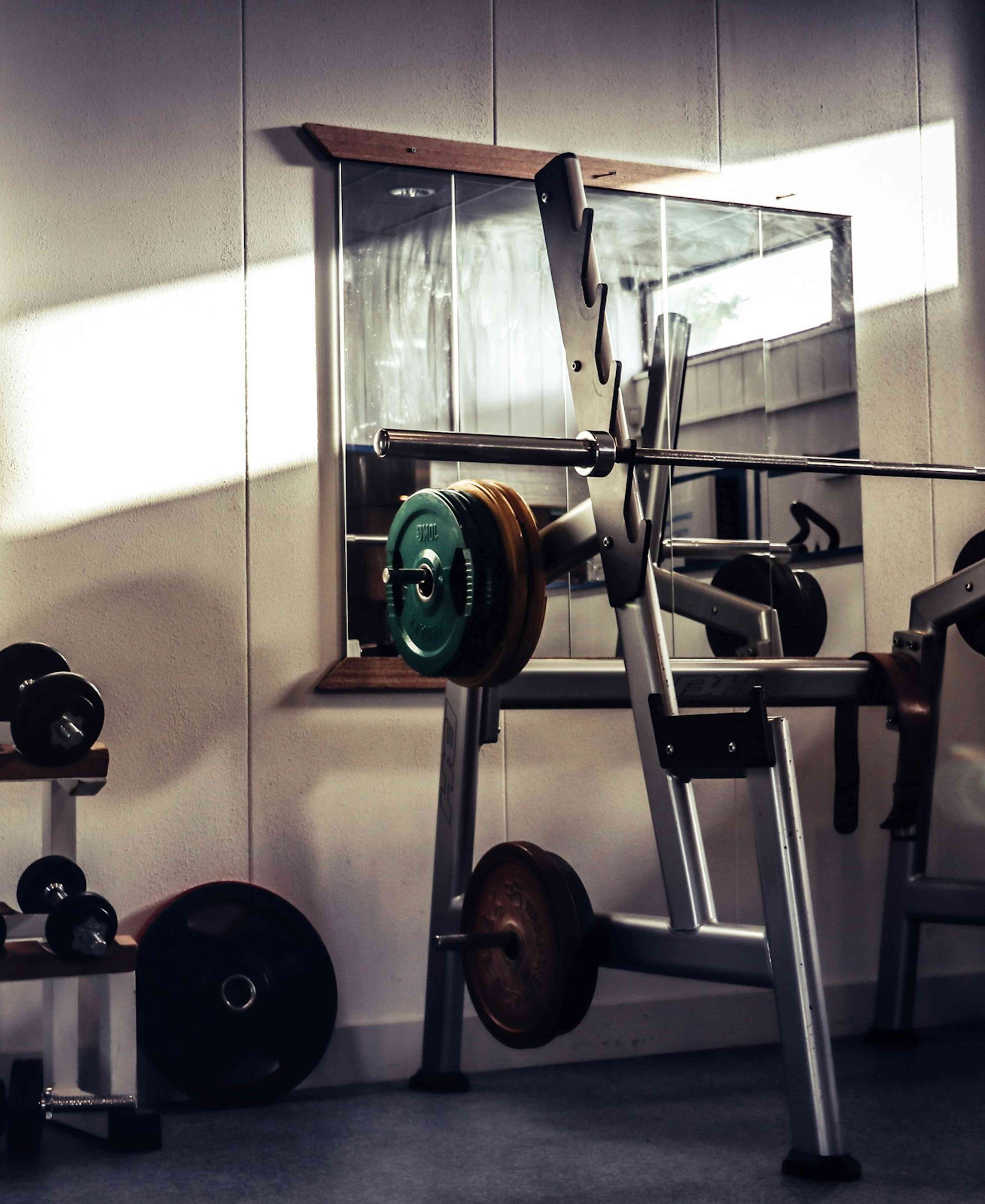 An indoor gym with sunlight streaming through a window onto weightlifting equipment