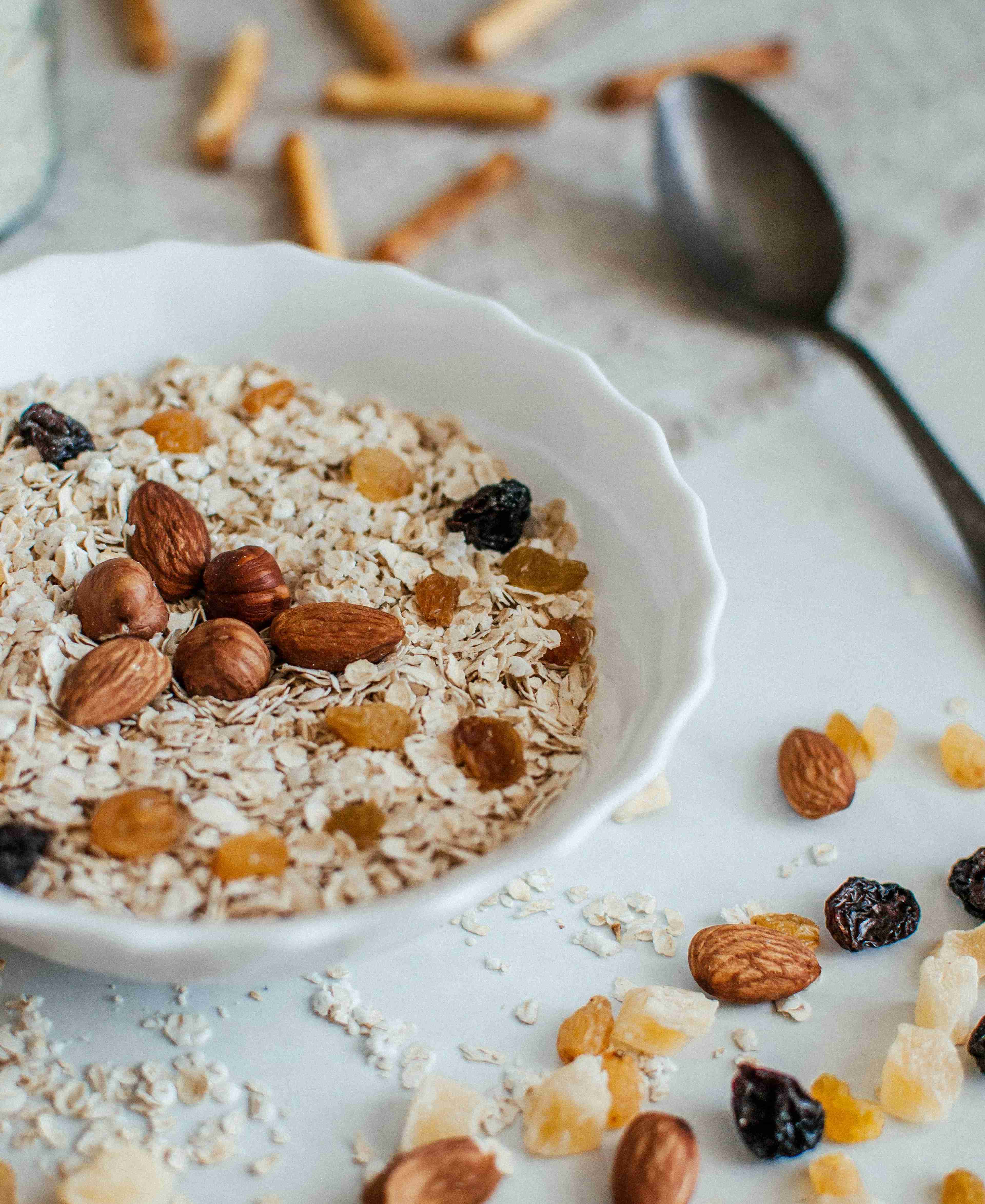 White bowl of oatmeal peppered with almonds and dried fruit