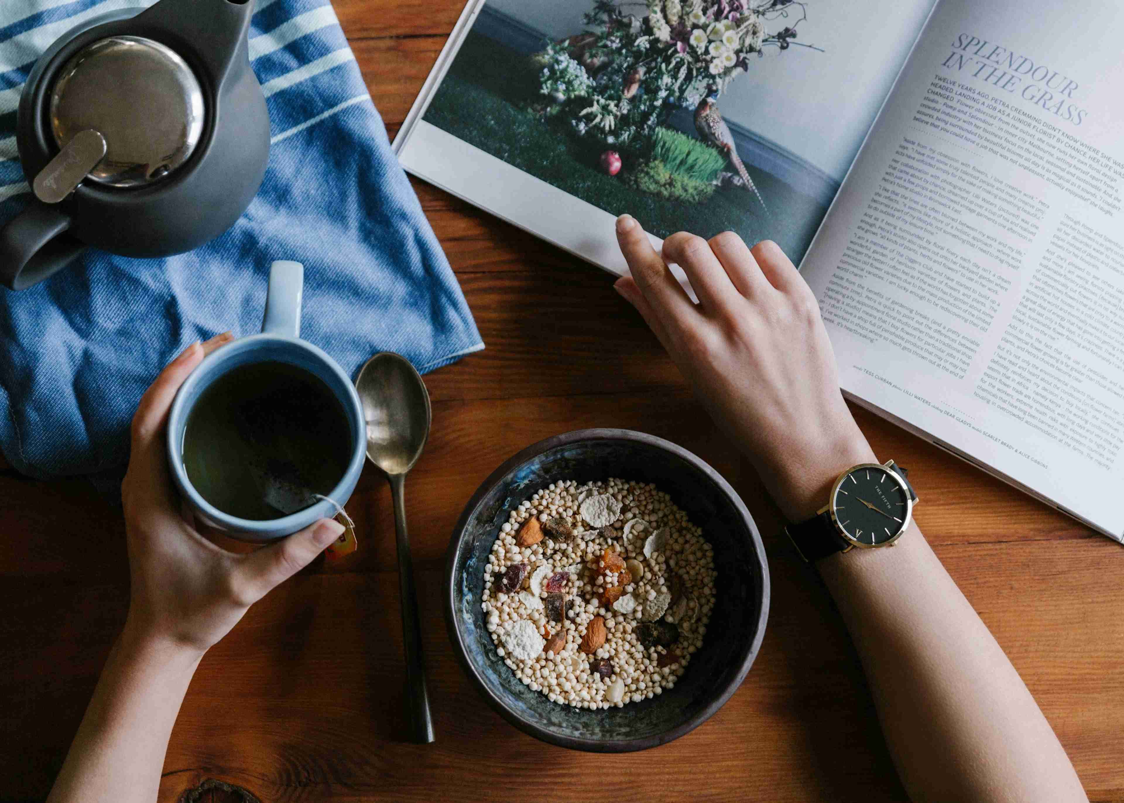 Woman holding blue ceramic mug and reading a white magazine