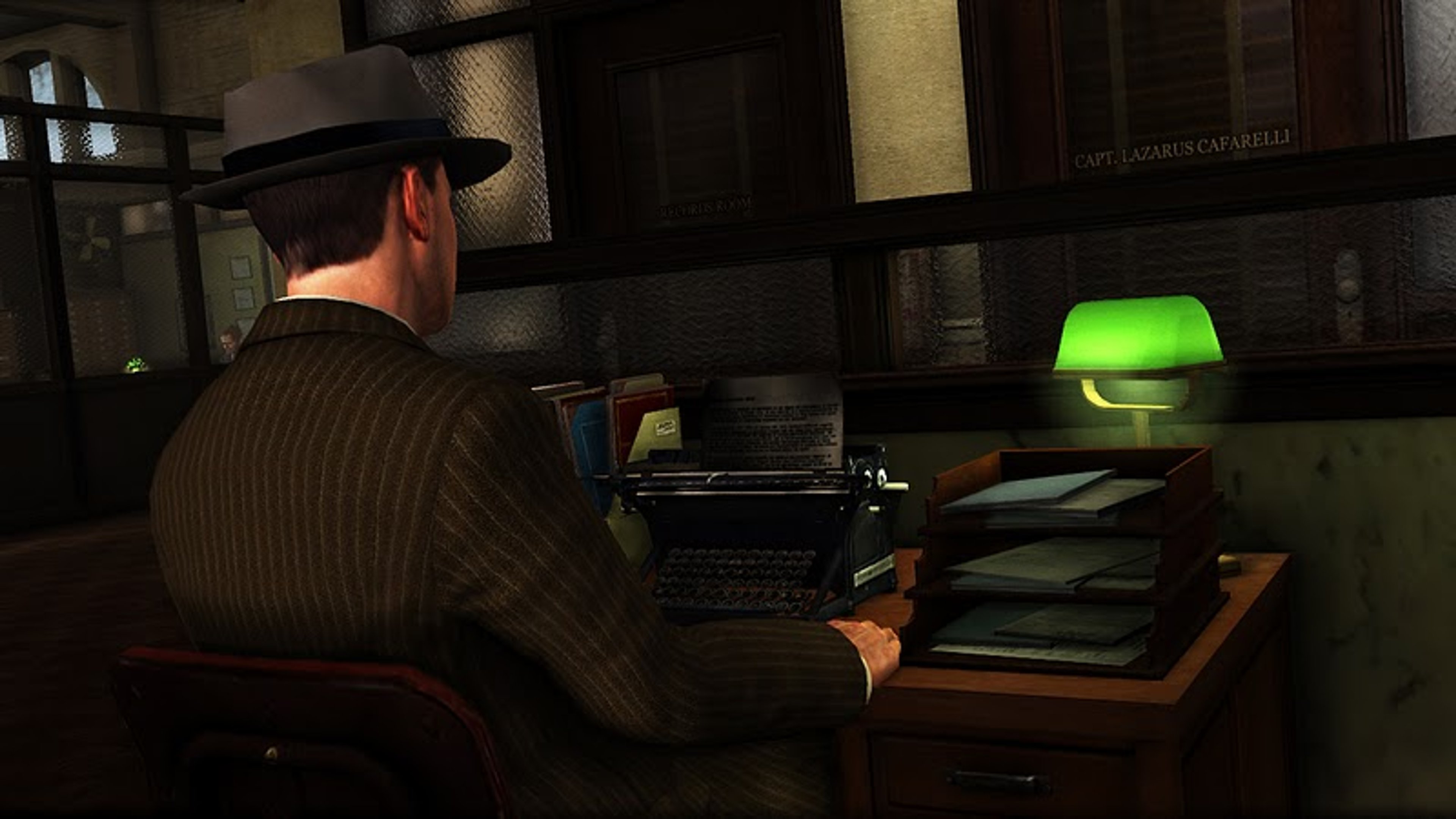 A grizzled, middle-aged man in a suit sitting at a desk