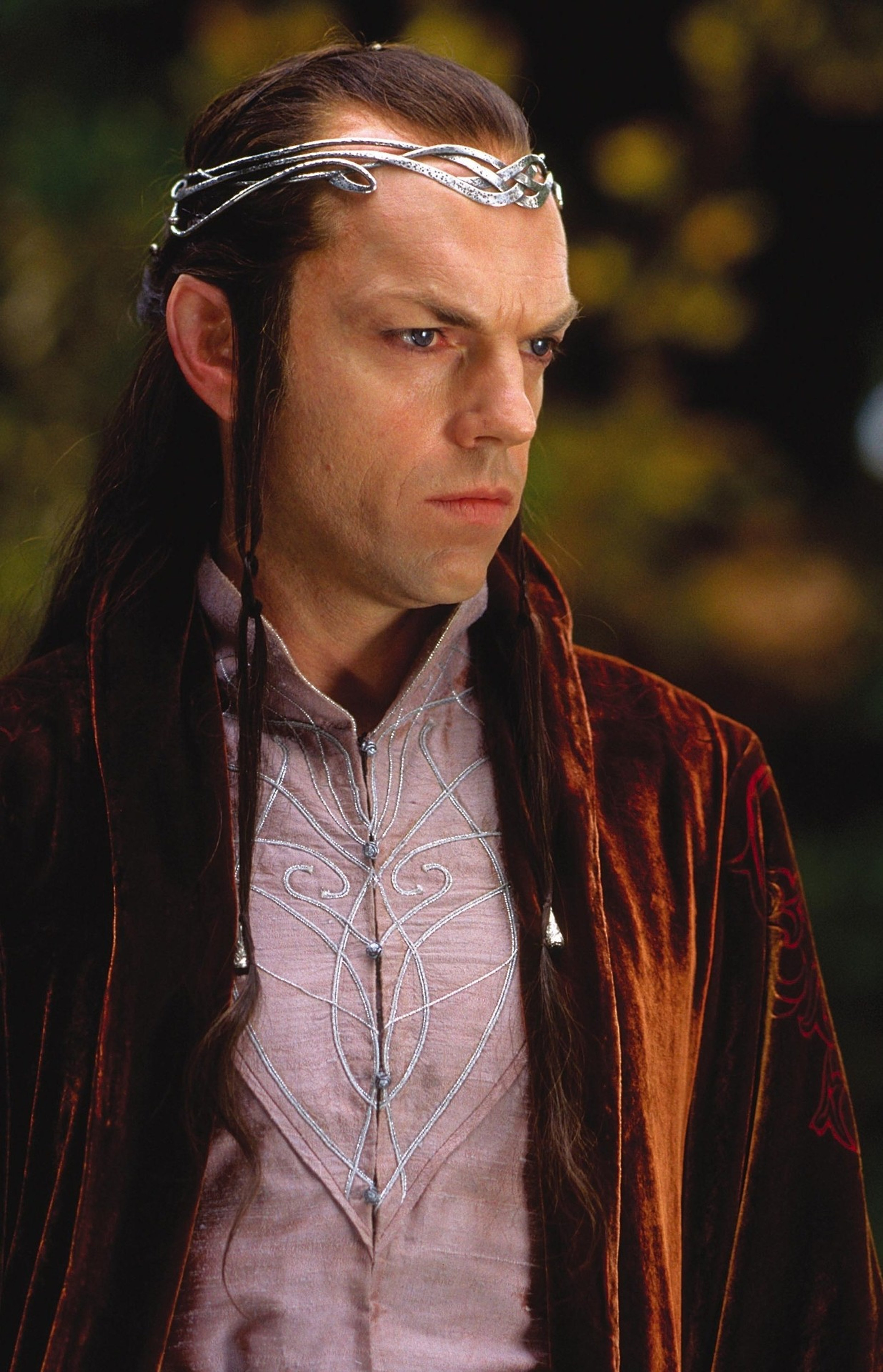 A male character with long dark hair, wearing a red velvet robe and a silver headpiece, with a serious expression on his face.