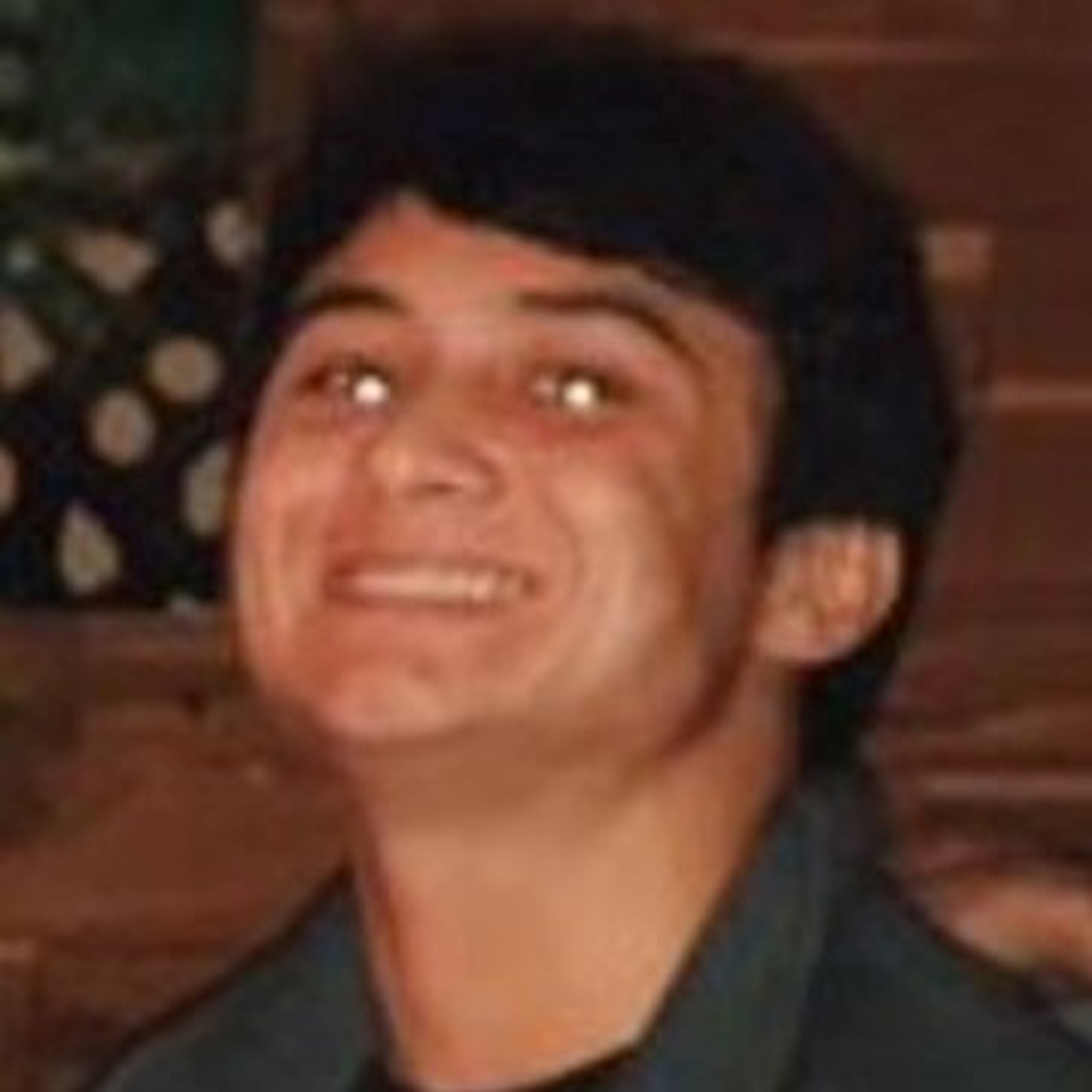 A young man with short dark hair smiling at the camera