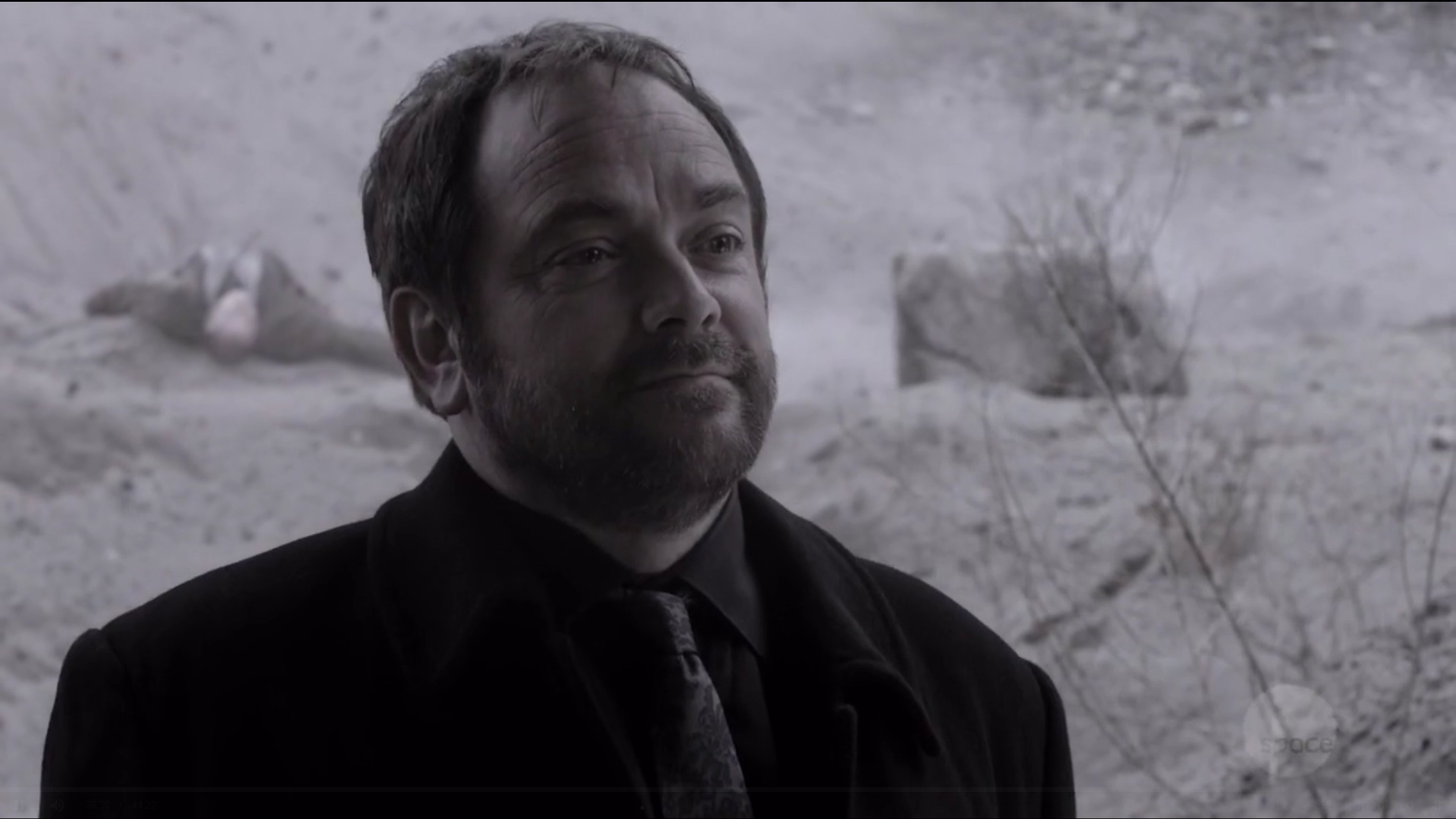 A man in a black suit standing in a snowy outdoor scene