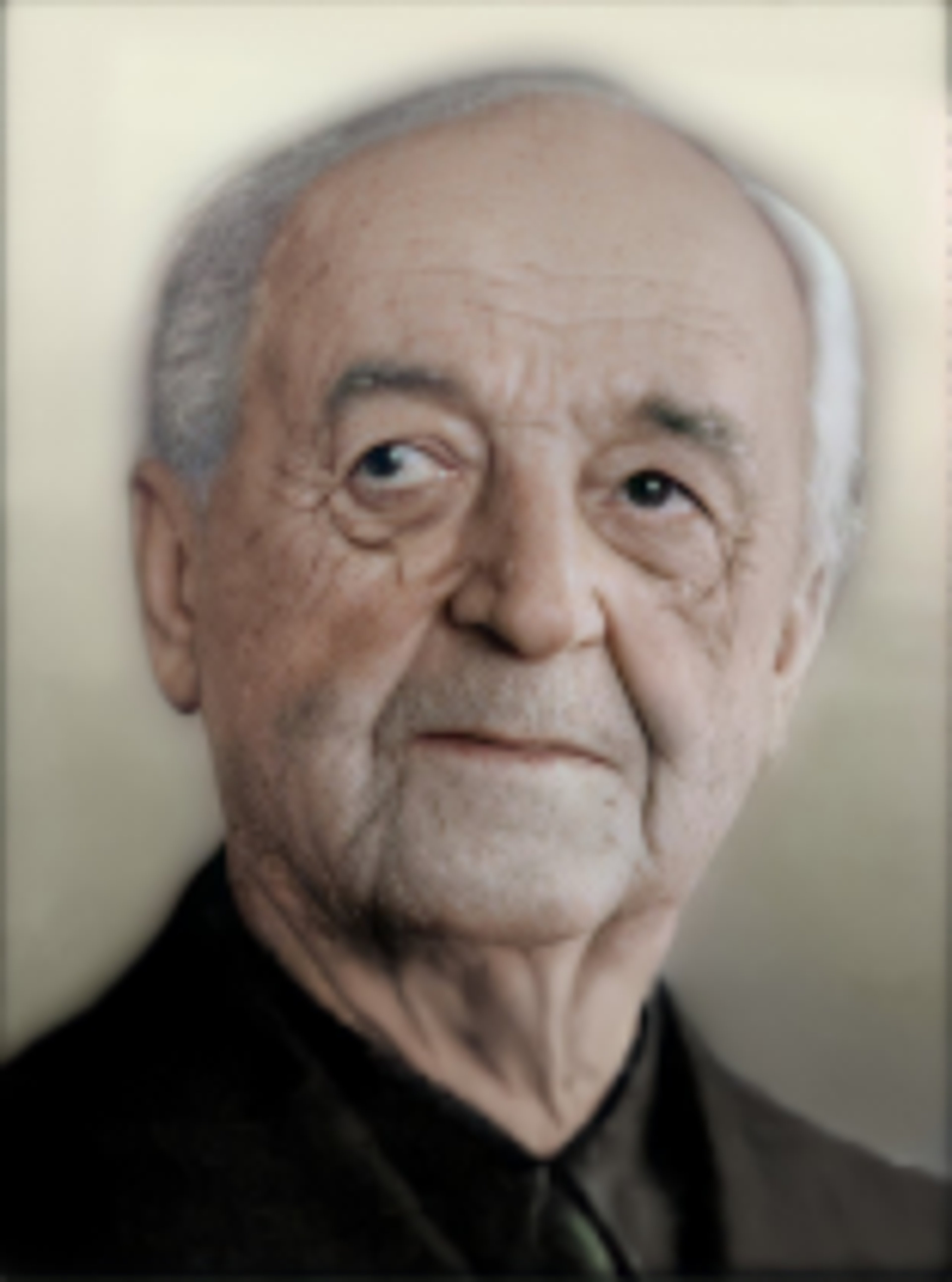 An elderly man with gray hair and a serious expression, wearing a dark suit.